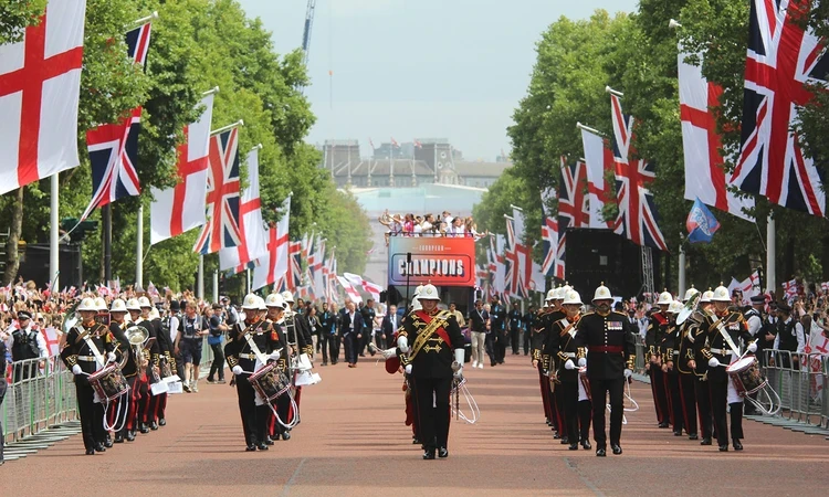 Military band leads the England Women's open-top bus down The Mall