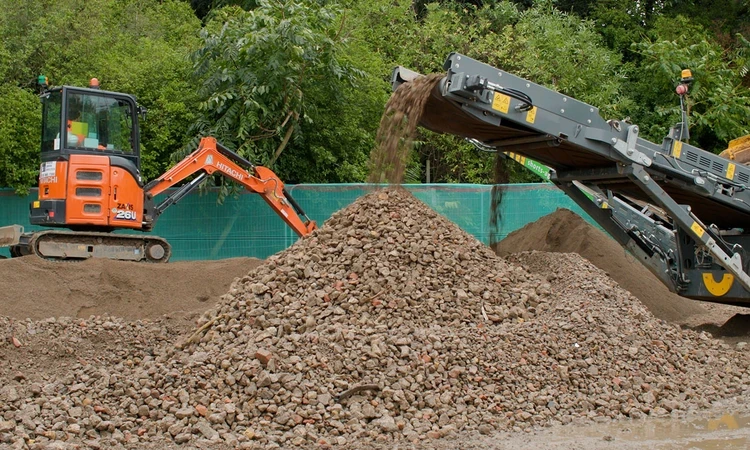 Heavy machinery sifting rubble from the old site into piles ready for reuse