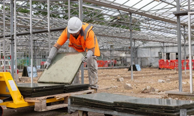 Workman collecting paving slabs from the old glasshouses for reuse in the new garden