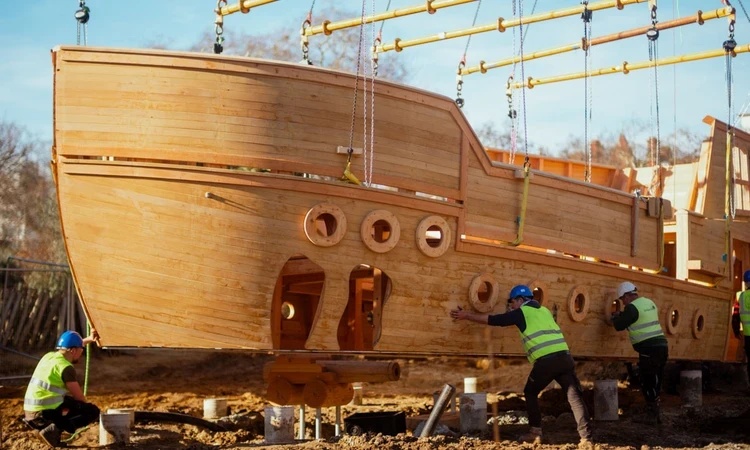 Workmen lower the new play galleon onto its foundations