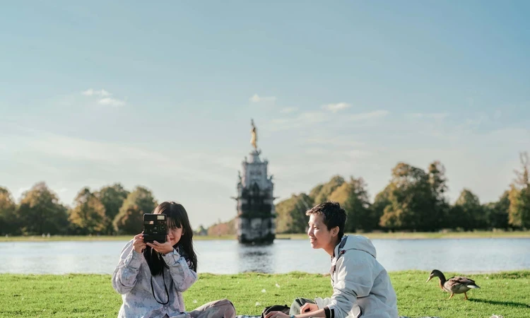 A couple picnicking and taking photography in Bushy Park