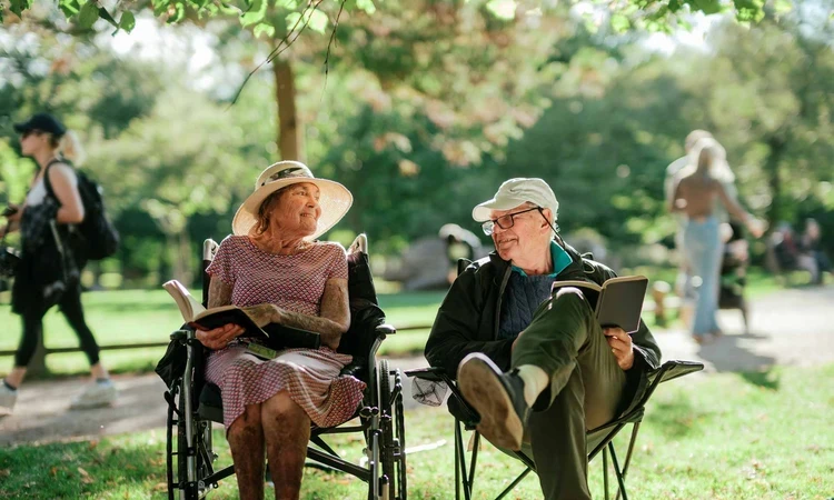 A couple reading while sitting on camping chairs in Bushy Park