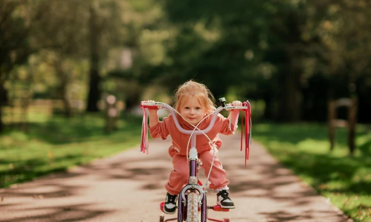 A young girl cycling through Bushy Park