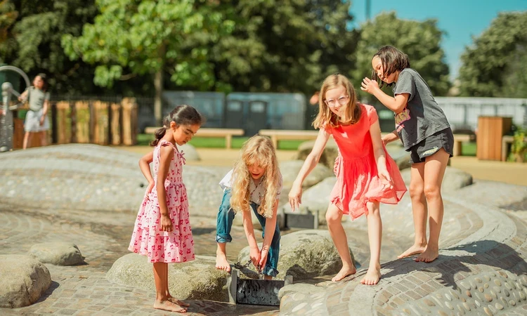 Four children playing with a playground water feature