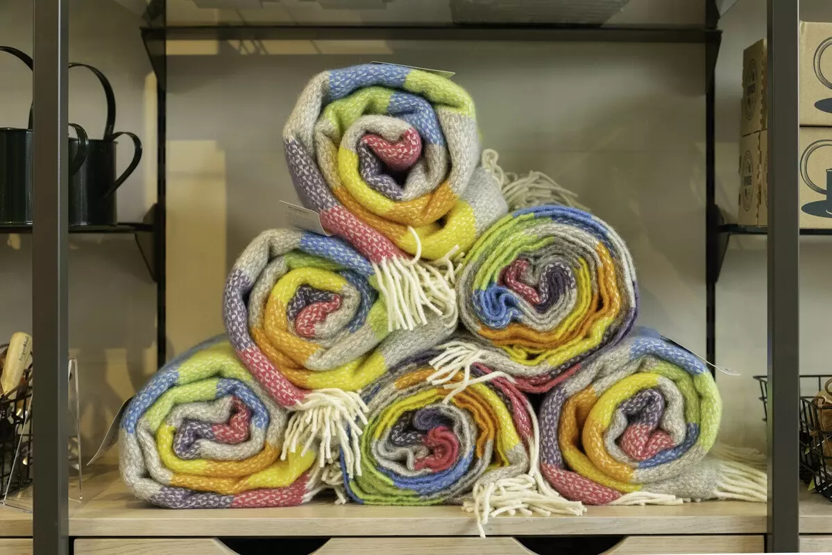 Multi-coloured wool blankets rolled up and organised in a pyramid. 