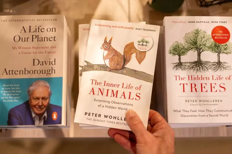 A hand holds up a copy of 'The Secret Life of Animals' book. The over features an illustrated squirrel. 