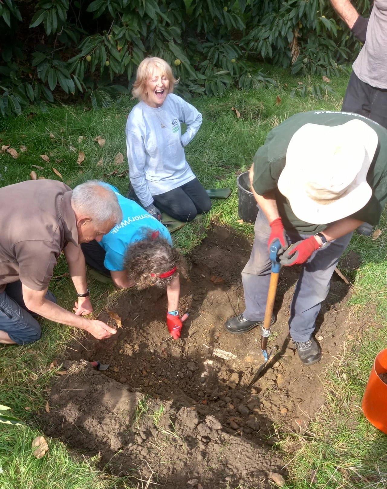 A group of volunteers working on the archaeological dig at the Keeper's Cottage - four people work at a trench in the grass