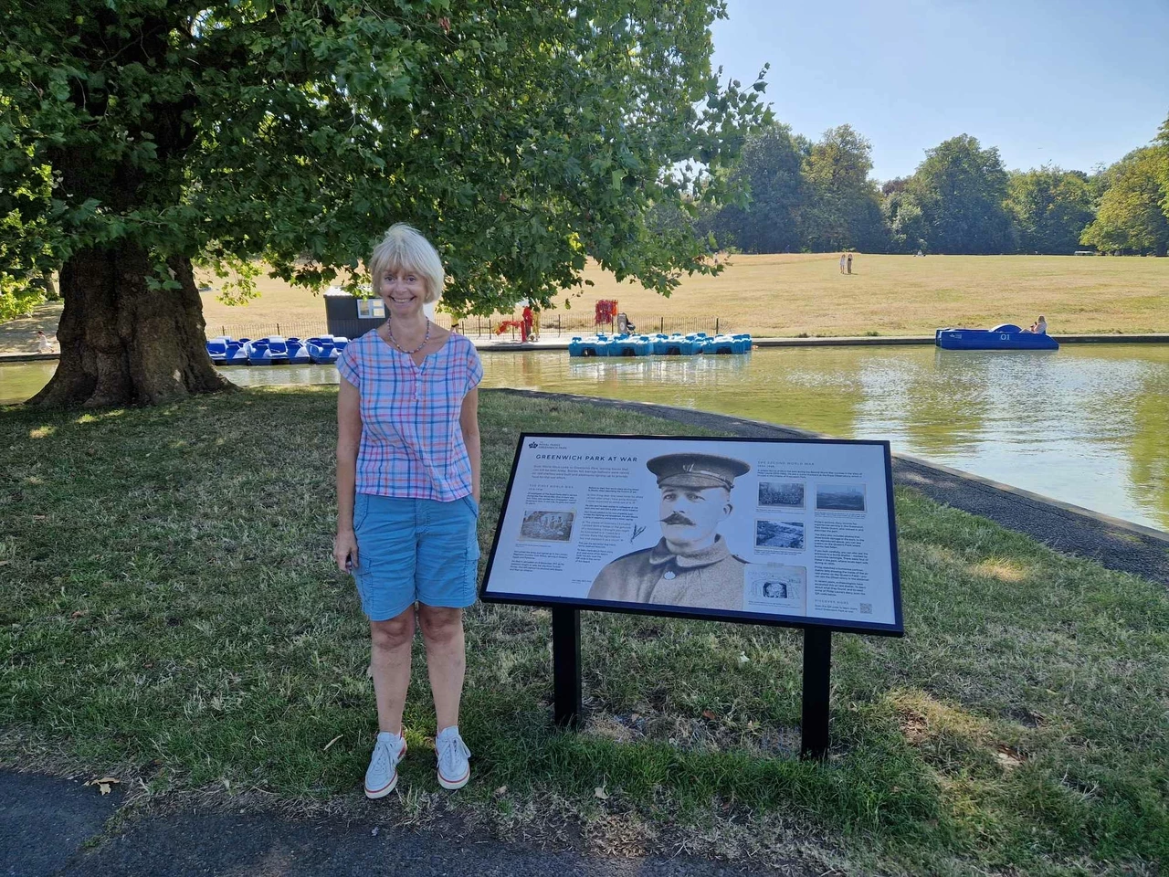 Sarah Gooch stands next to the new information board celebrating Hori Tribe's story at Greenwich Park