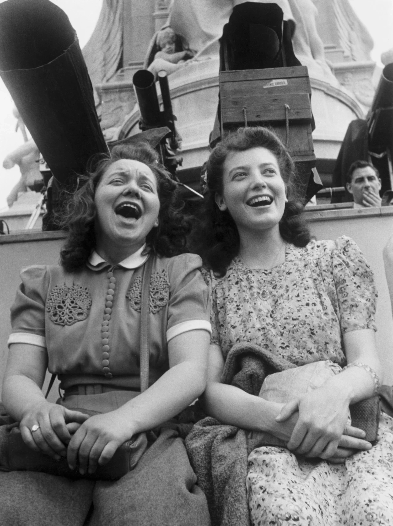 Two young women celebrating VE day on the Victoria Memorial outside Buckingham Palace, 8 May 1945 