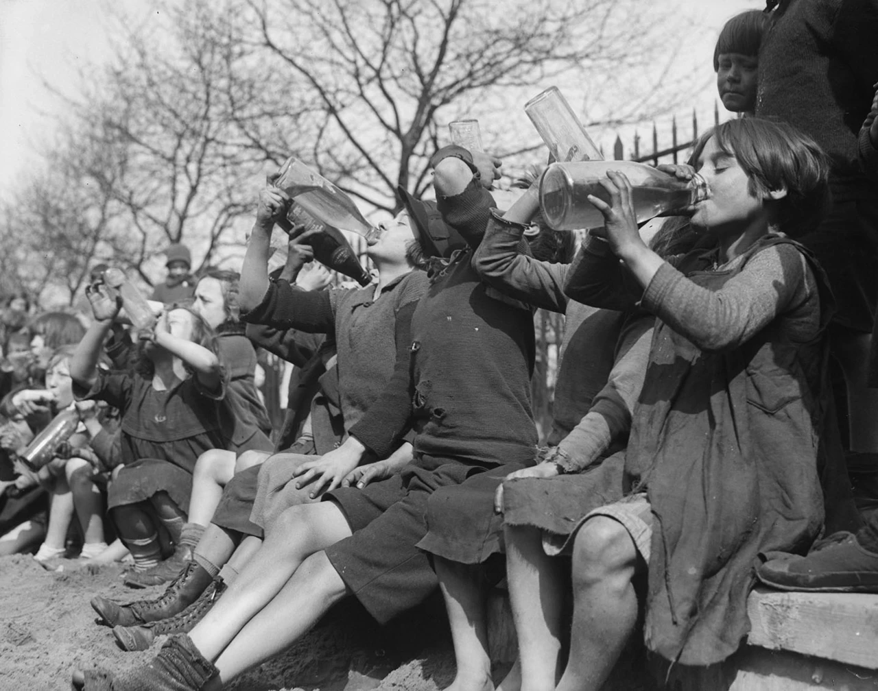 A ragged group of children cool themselves down with soft drinks