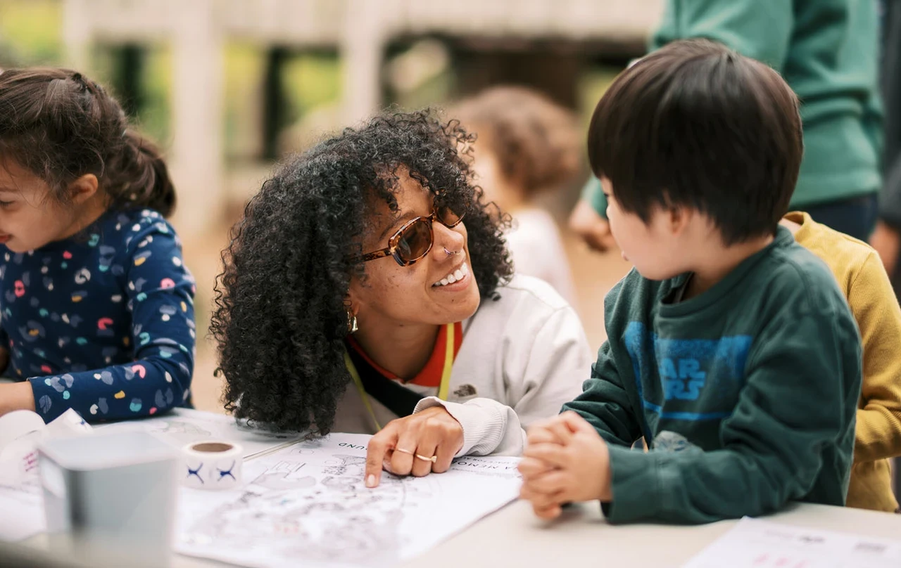 A woman in dark glasses talking to a young boy.