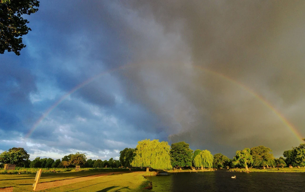 A rainbow arches through moody rainclouds above the park