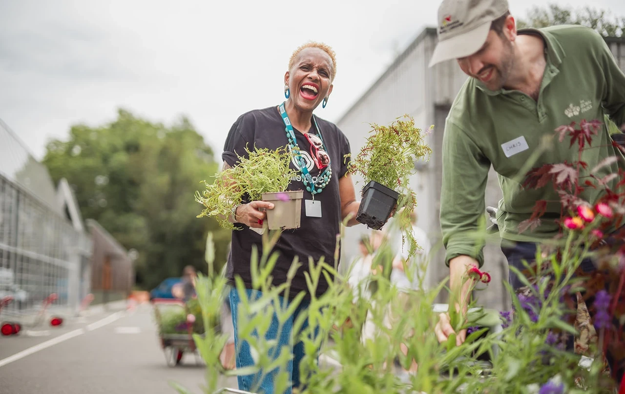 A smiling woman holding some pot plants
