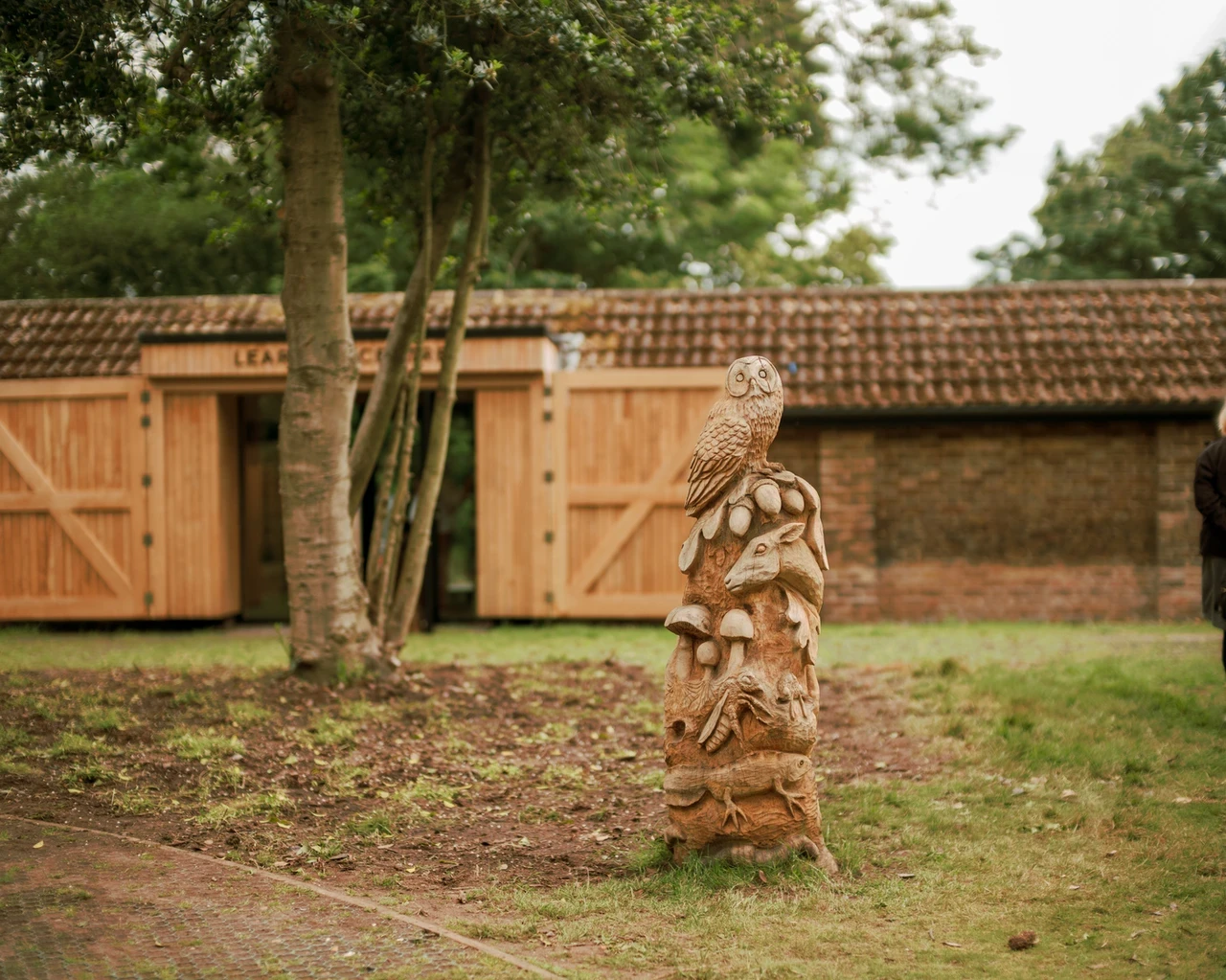 Image of the entrance to the Greenwich Park Learning Centre with a wooden carving of park wildlife in the foreground. 