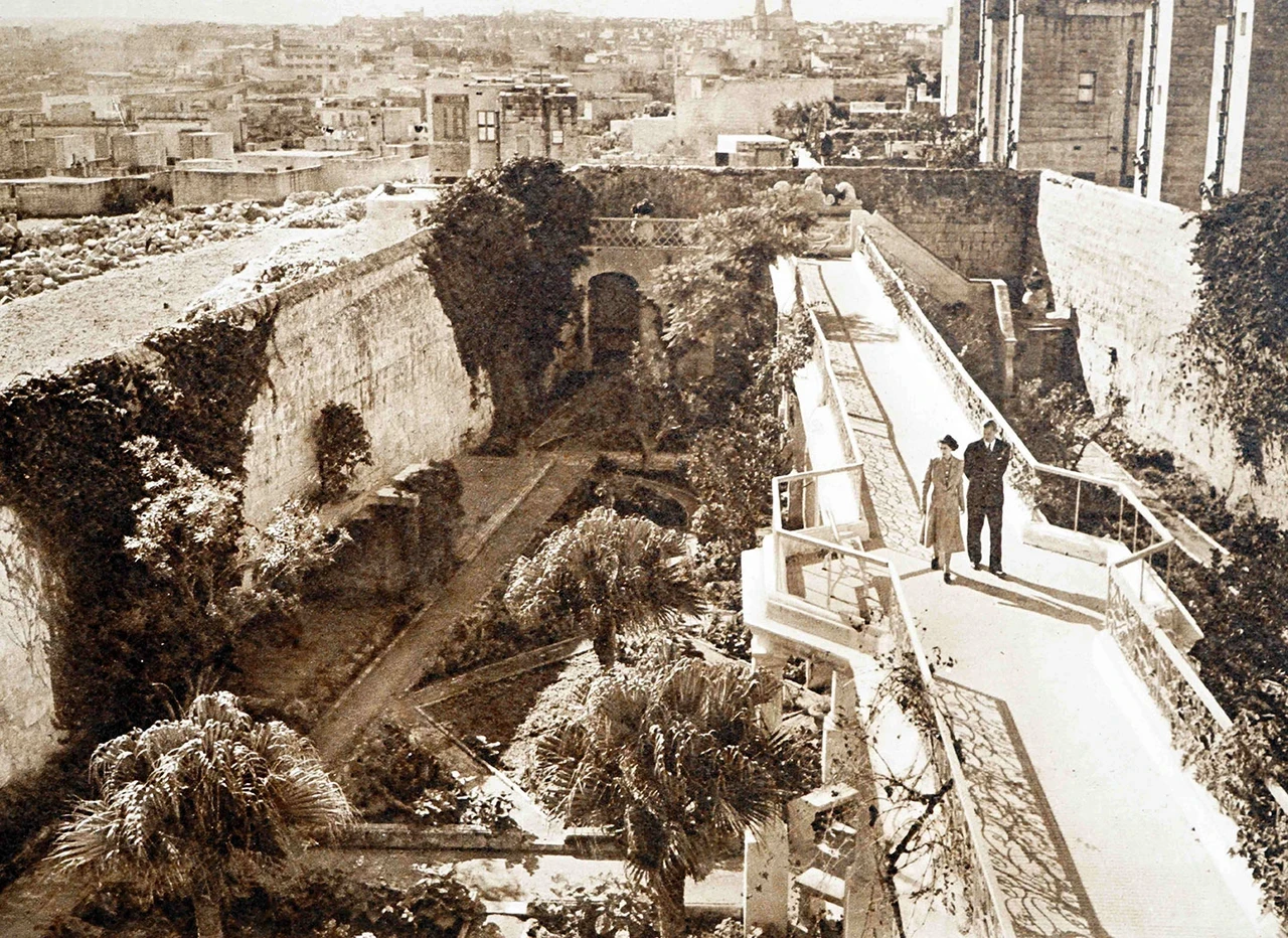 Princess Elizabeth II and the Duke of Edinburgh strolling through a garden in Malta