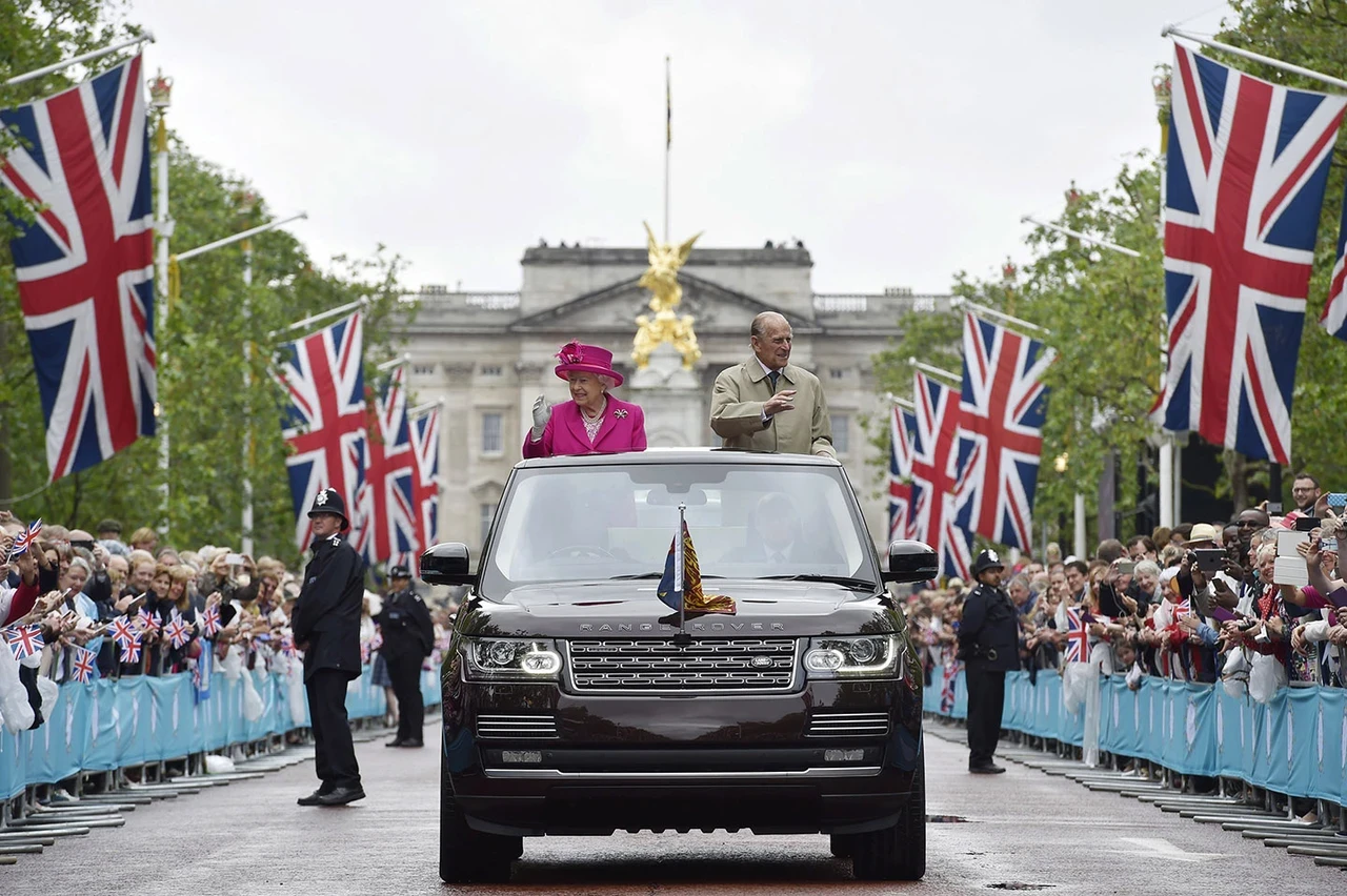 Queen Elizabeth II and Prince Philip, Duke of Edinburgh wave to crowds celebrating the monarch's 90th birthday